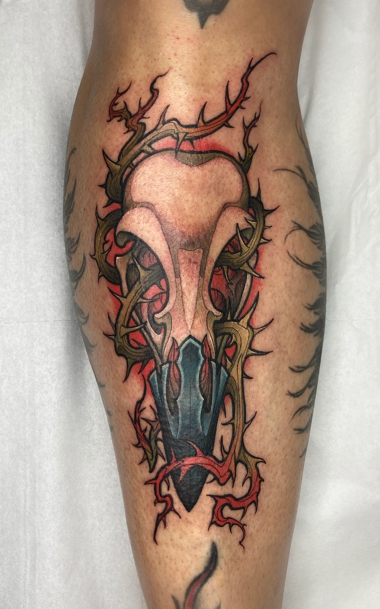 Tatouage néo-trad couleur représentant un crâne de corbeau sur le tibia – Jake Tattoo Parlor à Belfort.