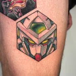 Tatouage couleur sur une cuisse représentant la tête du Gundam Aerial dans une alvéole – Jake Tattoo Parlor à Belfort.