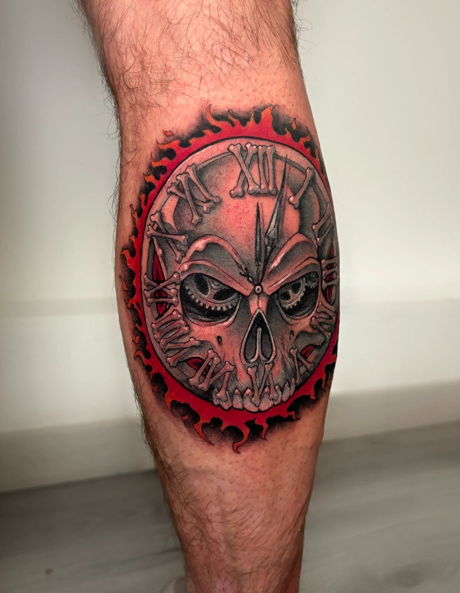 Tatouage d’horloge métallique en forme de crâne avec des flammes – Jake Tattoo Parlor à Belfort.