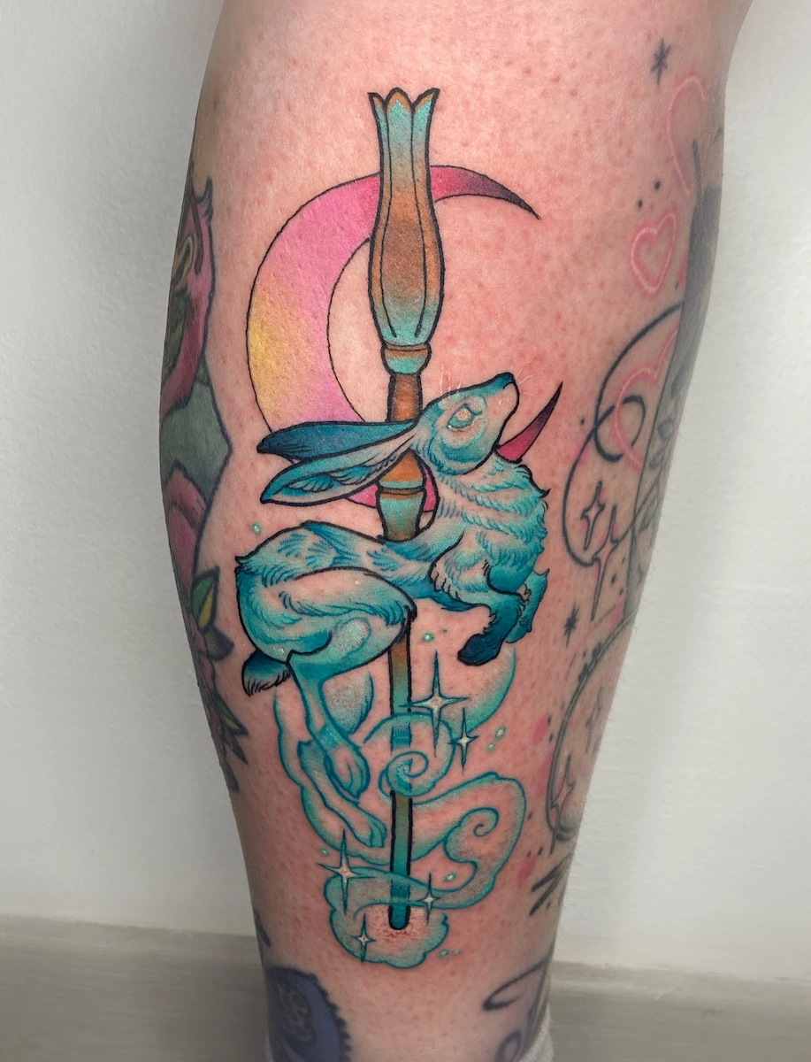 Tatouage néo-trad couleur inspiré de l’univers Harry Potter, représentant le Patronus de Luna Lovegood, un lièvre de lumière, avec sa baguette – Jake Tattoo Parlor à Belfort.