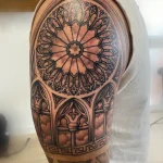 Tatouage ornemental noir et gris représentant une rosace de cathédrale – Jake Tattoo Parlor à Belfort.