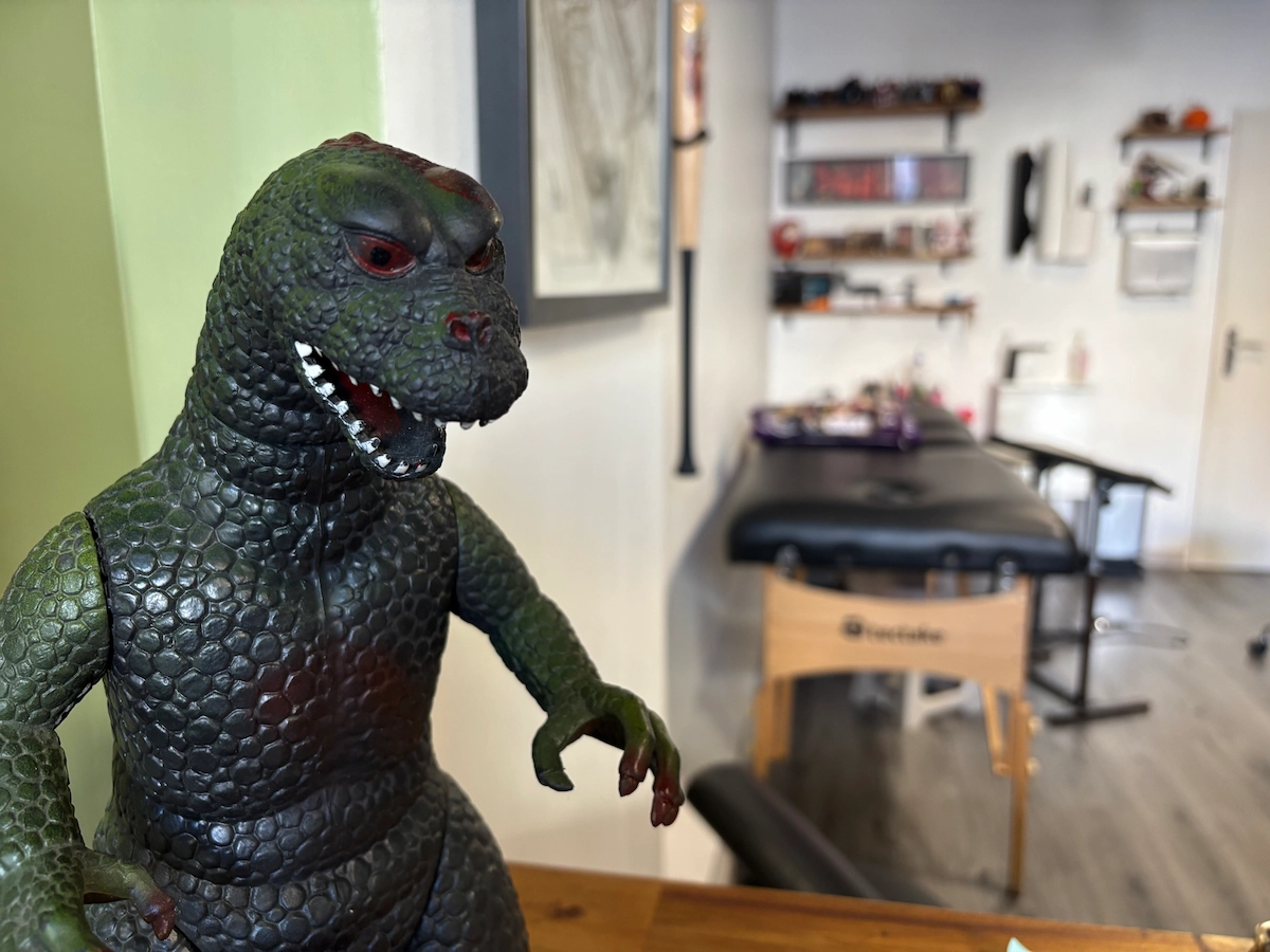 Photo du salon avec figurine Godzilla illustrant l’ambiance pop et détendue chez JAKE Tattoo Parlor